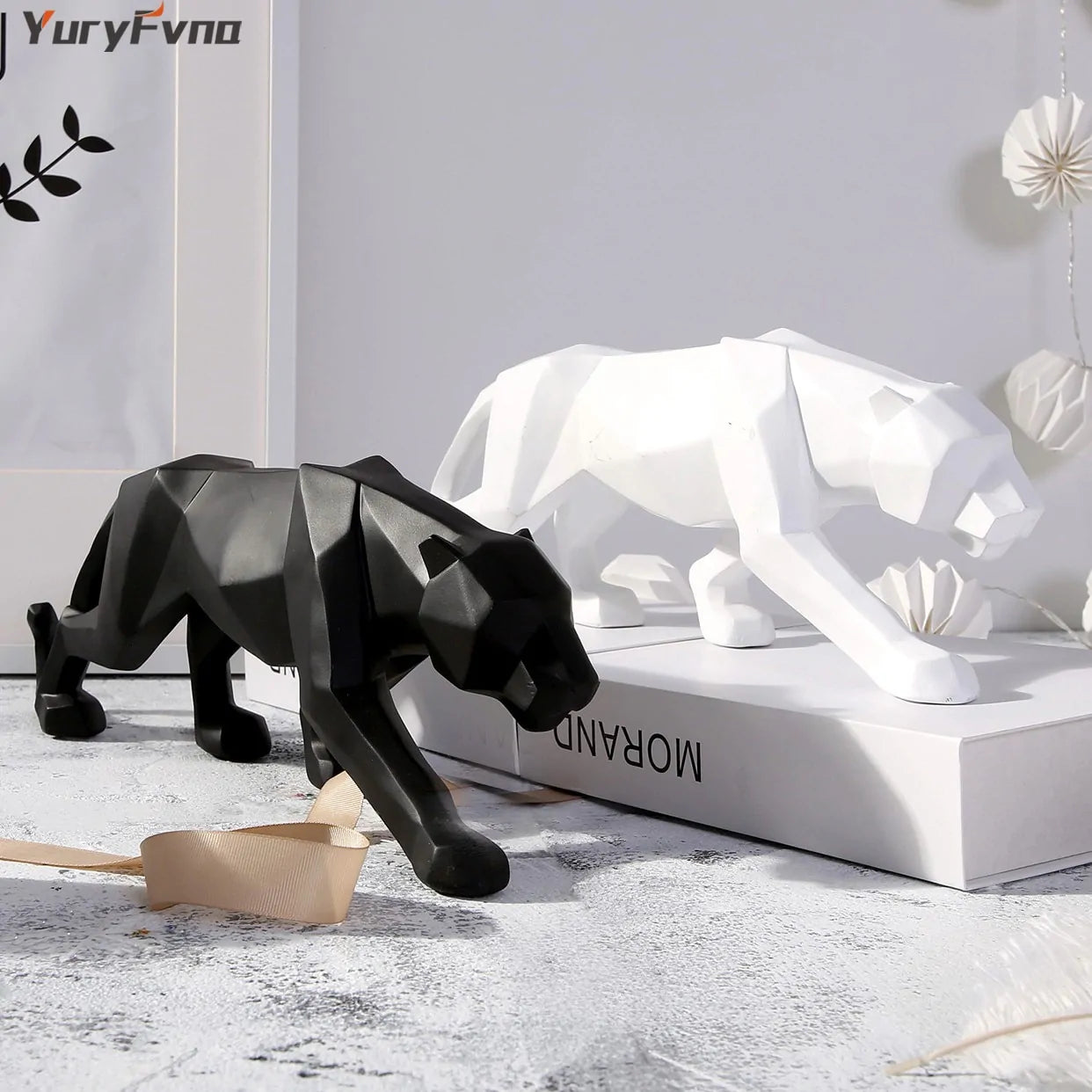 Two resin leopard statues, one in black and one in white, placed on a surface with a decorative background.