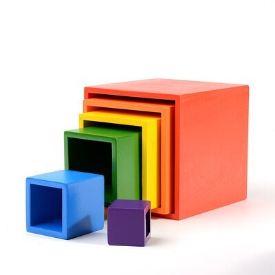 A set of solid wooden toys in various colors including red, orange, green, blue, and purple, stacked together with a red arched wooden storage box.