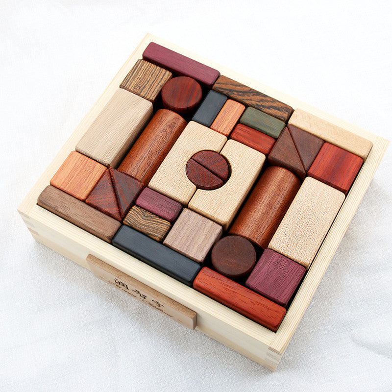 A set of wooden block toys in various shapes and colors neatly assembled in a wooden box.