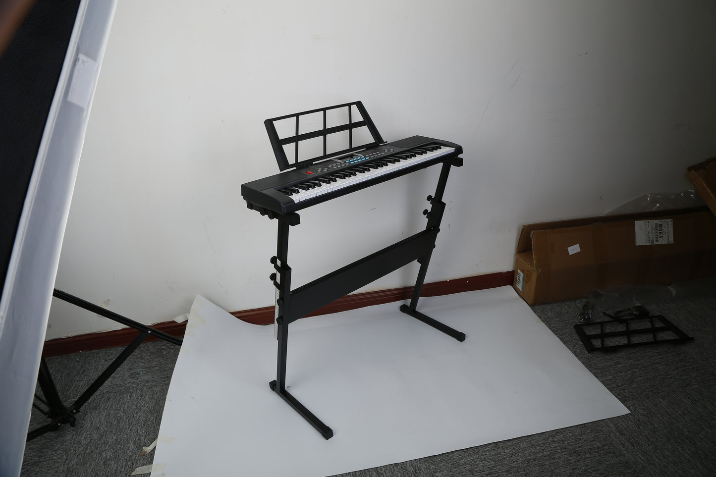 Keyboard on a stand in a room with a white sheet and cardboard box.