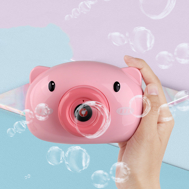 A pink bubble machine camera designed to look like a pig, with a person's hand creating bubbles in the background.
