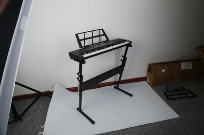 Keyboard on a stand in a room with a white sheet and cardboard box.