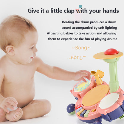 Baby playing with a colorful toy drum set on a white background